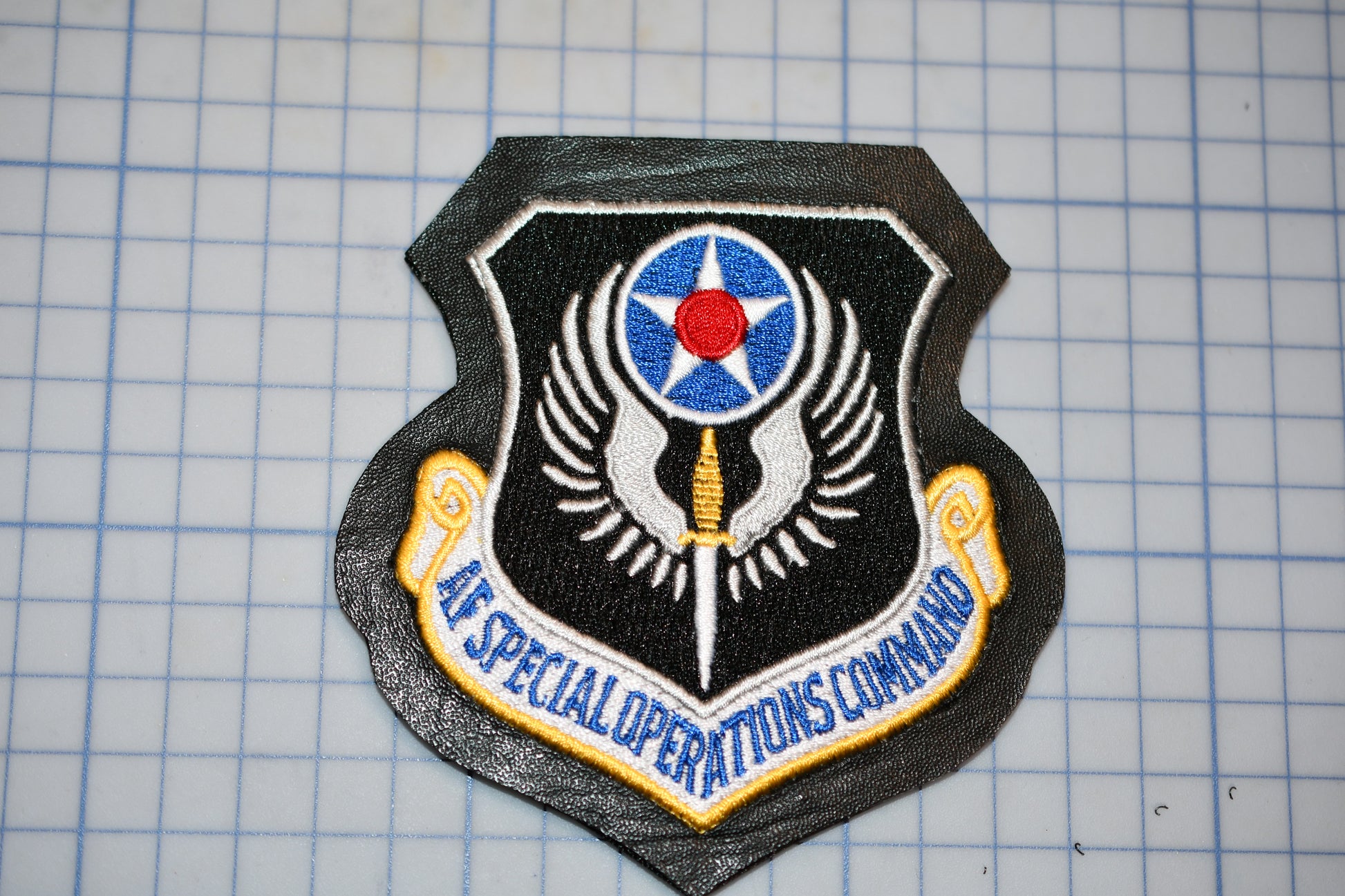 a black and gold emblem with a red star and a blue and white shield, which appears to be a military insignia.