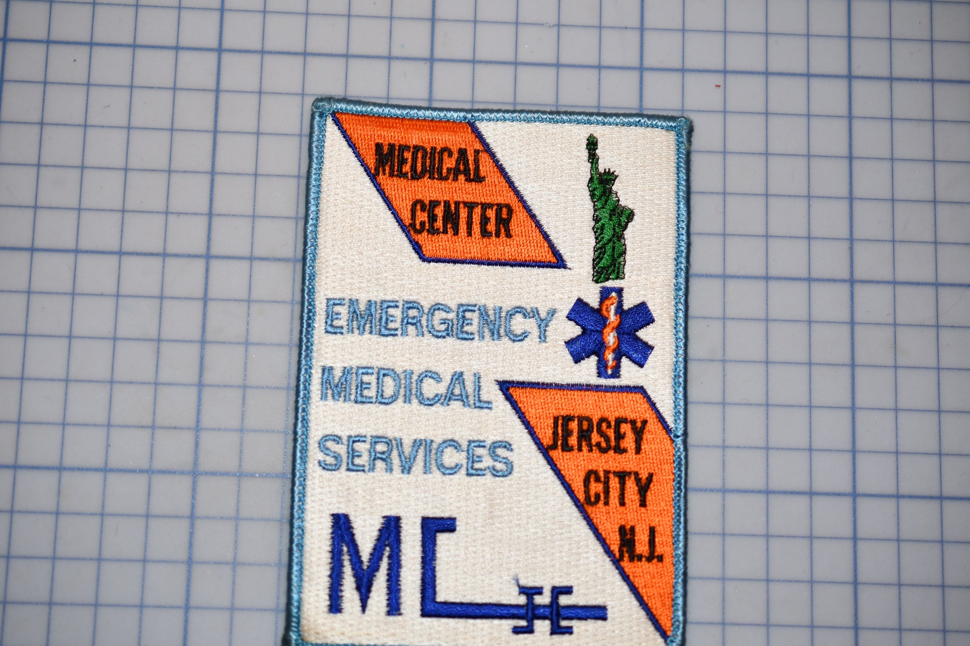 a patch with text and a symbol, including the words "MEDICAL CENTER", "EMERGENCY MEDICAL SERVICES", and "JERSEY CITY N.J."