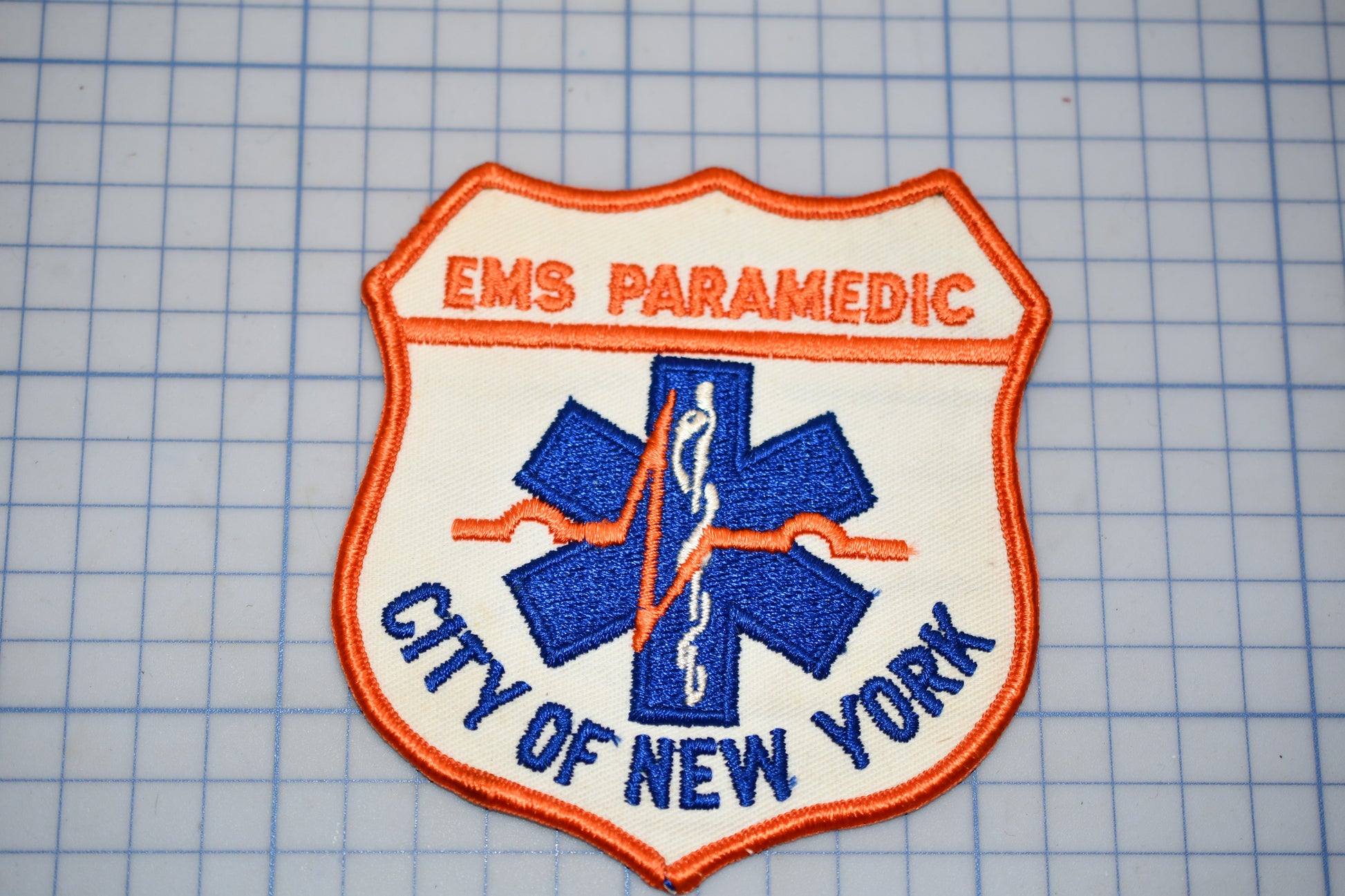a patch with the text "EMS PARAMEDIC" and "CITY OF NEW YORK" on it, along with a blue and white medical symbol.