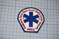 a patch with a blue cross symbol and text surrounding it, which appears to be a medical or emergency service patch.