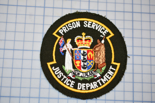 a circular emblem with text and a coat of arms, which appears to be a symbol or insignia associated with the Prison Service Justice Department.