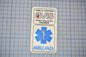 a white patch with text and a medical symbol, placed on a blue grid background.