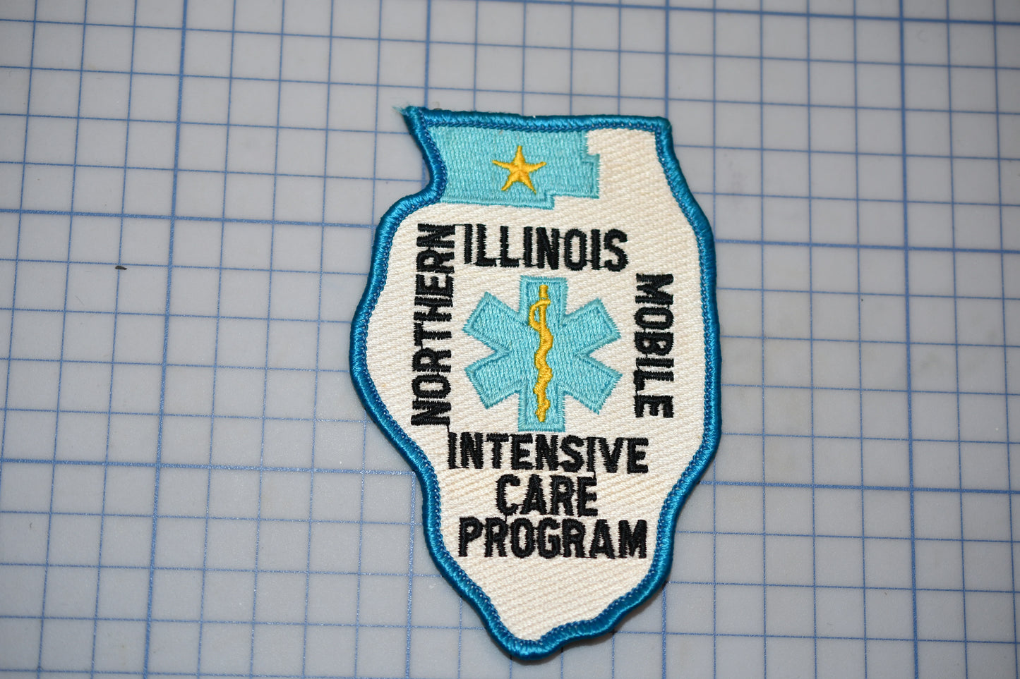 A patch with the text "NORTHERN ILLINOIS MOBILE INTENSIVE CARE PROGRAM" and a medical symbol, likely representing a healthcare program or organization.