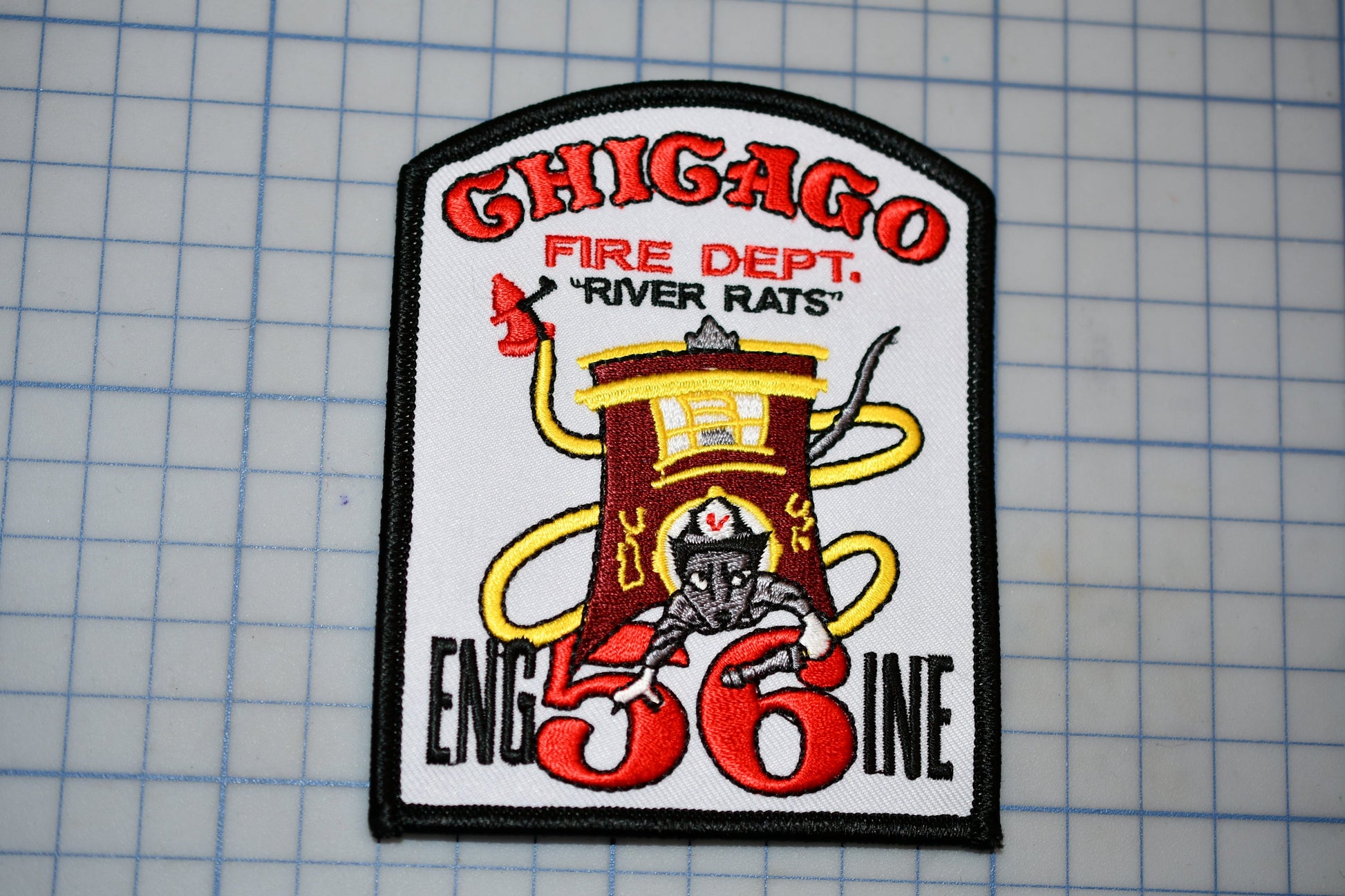 A patch with the text "CHICAGO FIRE DEPT. 'RIVER RATS'" and an illustration of a fire hydrant with a yellow hose. The patch also features the number "56" and the text "ENGIN 36".