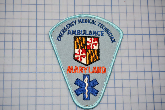 a patch with the text "EMERGENCY MEDICAL TECHNICIAN AMBULANCE" and "MARYLAND" printed on it, along with a shield-shaped emblem and a blue medical cross symbol.