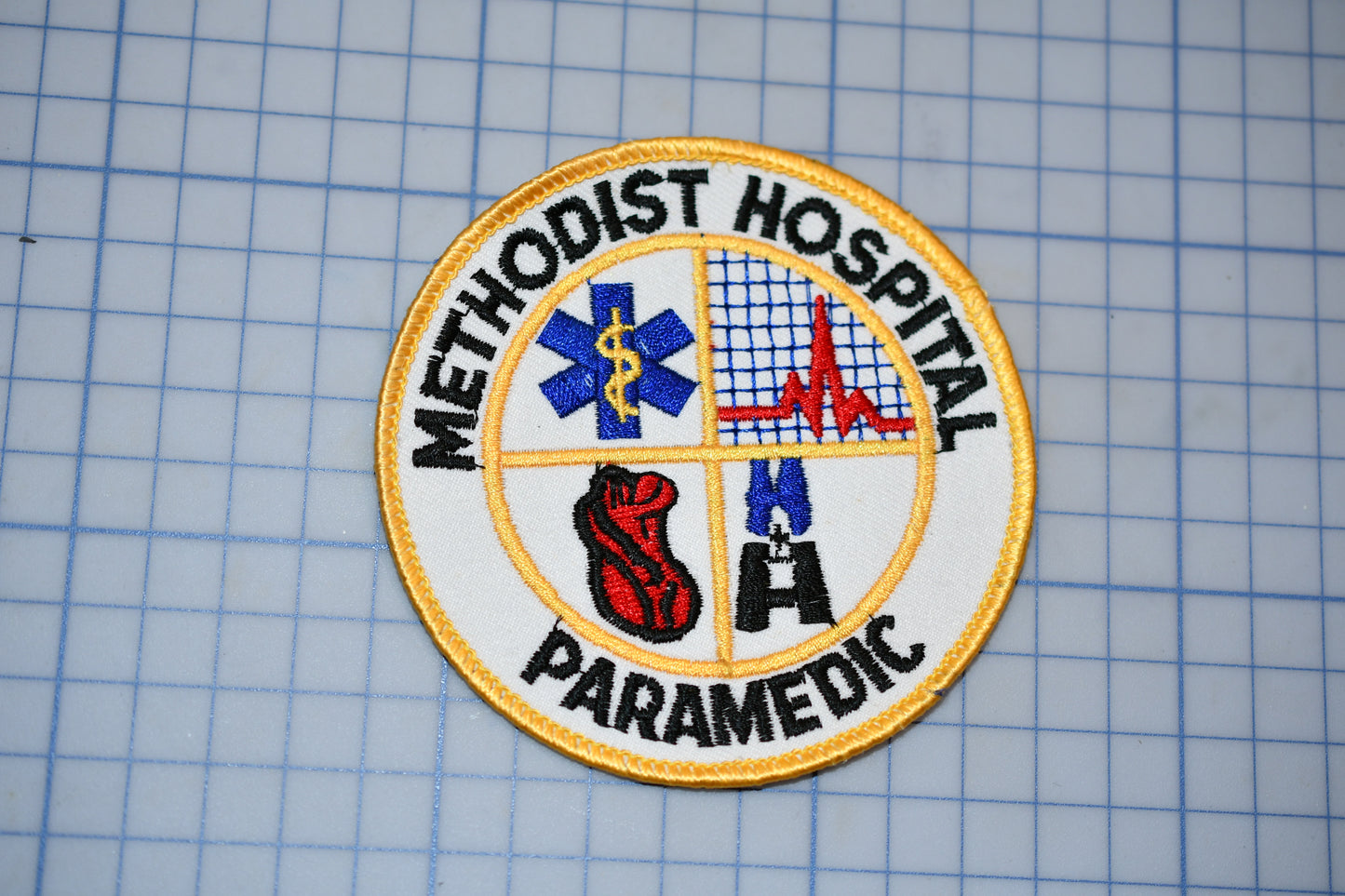 a badge or patch with the words "Methodist Hospital Paramedic" and various medical and emergency-related symbols, such as a cross, a heart, and a stethoscope.