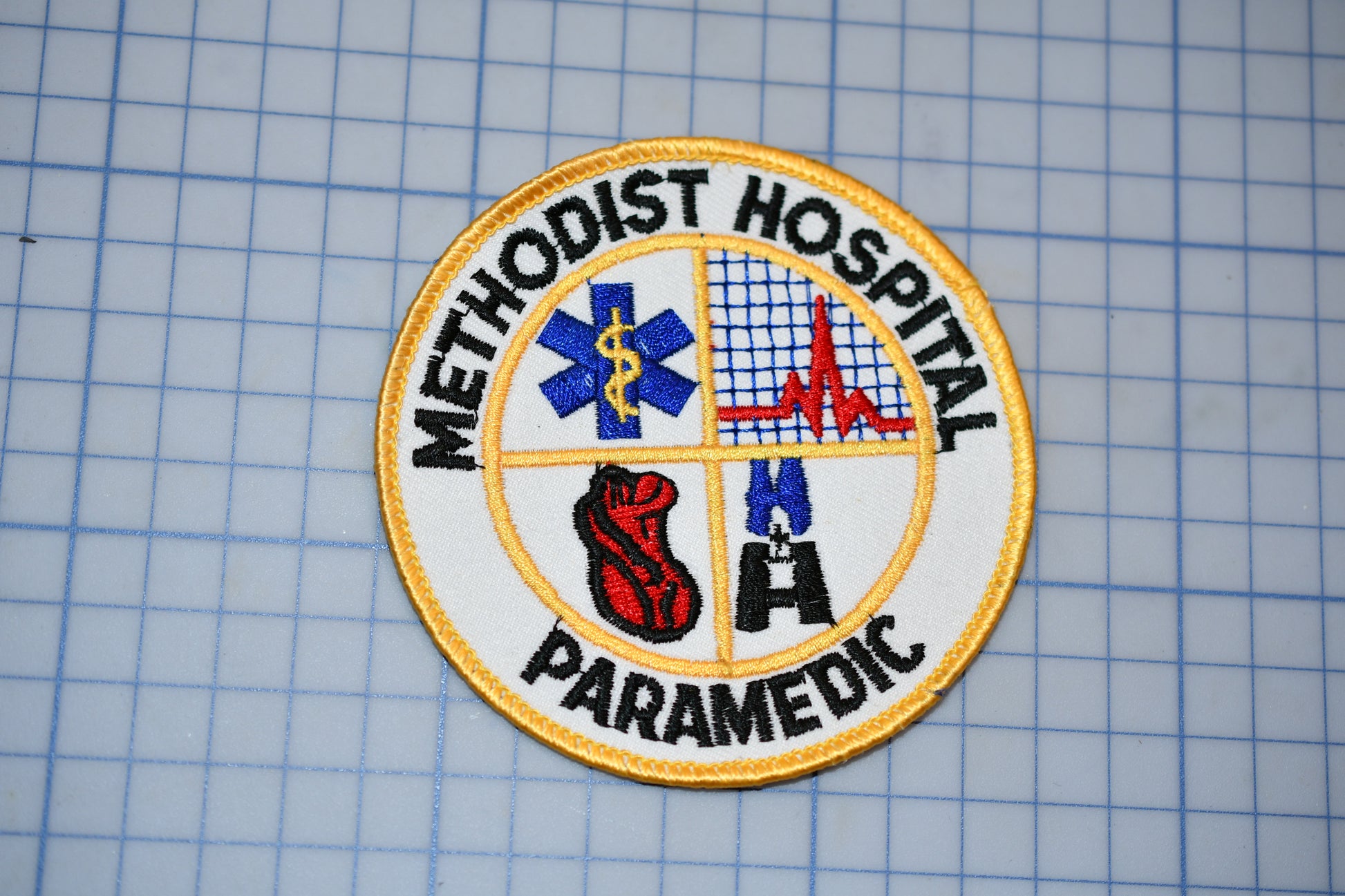 a badge or patch with the words "Methodist Hospital Paramedic" and various medical and emergency-related symbols, such as a cross, a heart, and a stethoscope.