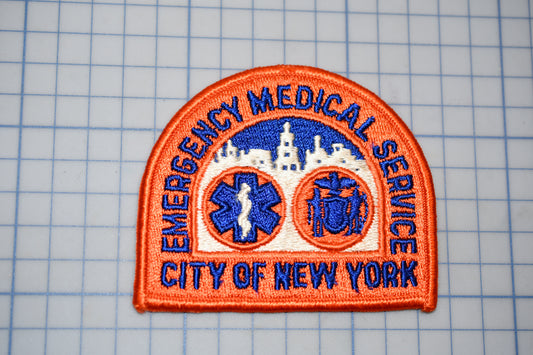 a patch with the text "EMERGENCY MEDICAL SERVICE CITY OF NEW YORK" and two medical symbols, one of which is a cross and the other a stethoscope.