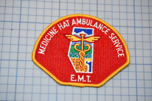 a red and gold patch with the text "EMT" and a medical symbol, indicating it is a patch representing the Emergency Medical Technician (EMT) service.