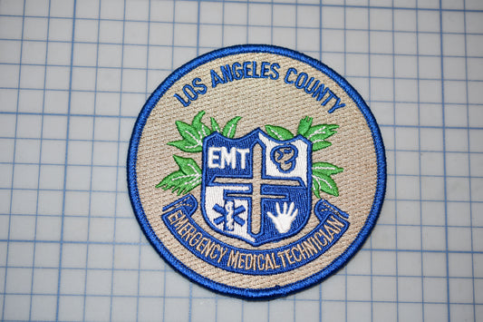 a badge or patch with the text "Los Angeles County EMT Emergency Medical Technician" and a shield-like emblem with a cross and leaves.