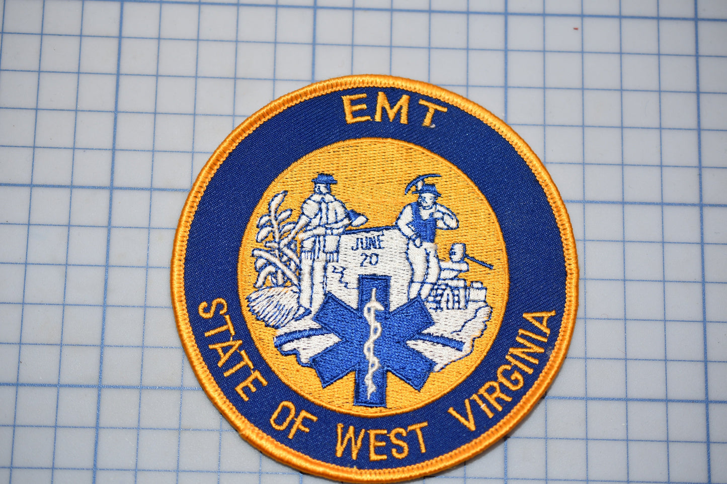 a patch with the text "EMT" and "STATE OF WEST VIRGINIA" on it, along with a blue and yellow design.