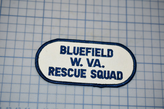 A patch with the text "BLUETFIELD W. VA. RESCUE SQUAD" printed on it, indicating that it is a patch from the Bluefield Rescue Squad.