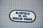 A patch with the text "BLUETFIELD W. VA. RESCUE SQUAD" printed on it, indicating that it is a patch from the Bluefield Rescue Squad.