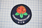 A circular patch with a red flower and green leaves, along with the text "CHRISTMASFIRES2001 N SW" printed on it.
