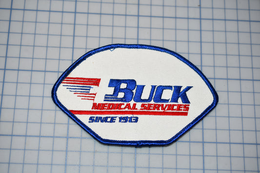A patch with the text "BUCK MEDICAL SERVICES" and "SINCE 1913" printed on it, along with a red and blue design element.
