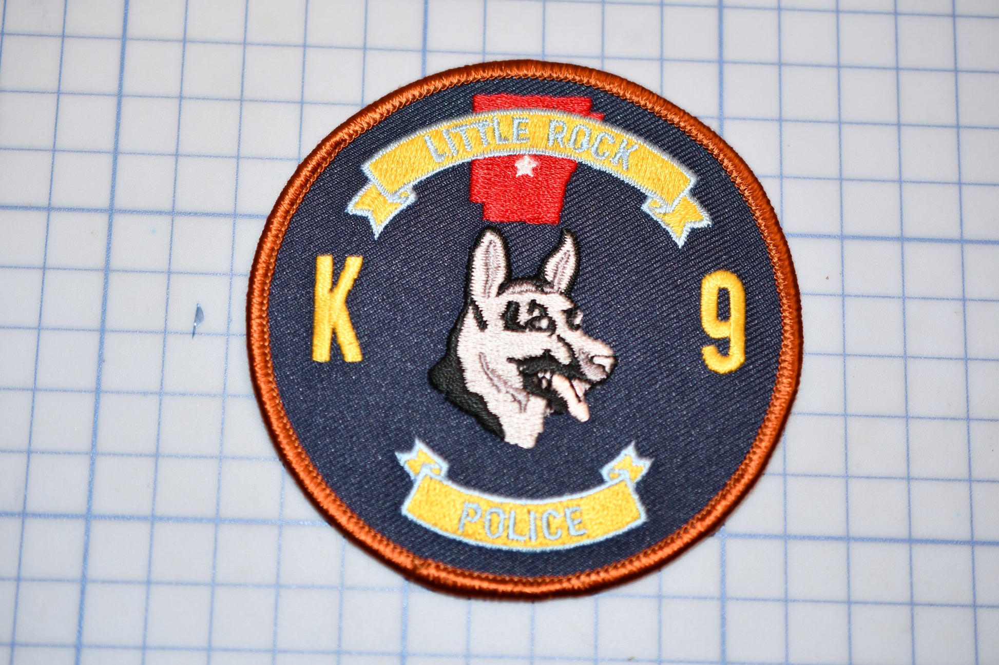 A circular patch with a dog's head and the text "Little Rock Police" on it, along with the number "9".