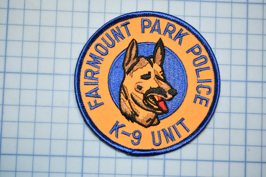 a badge with a dog's head and tongue, surrounded by text that reads "FAIRMOUNT PARK POLICE K-9 UNIT".