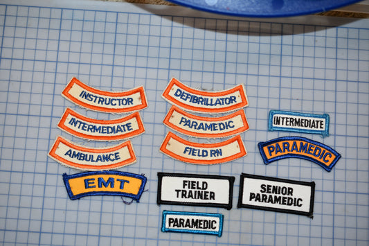 a collection of patches or badges representing various emergency medical services roles, including an instructor, defibrillator, paramedics, field nurse, ambulance, EMT, field trainer, senior paramedics, and paramedics.