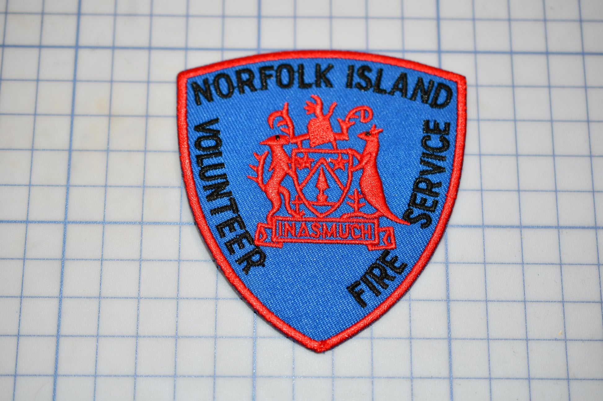 A blue and red patch with the text "NORFOLK ISLAND VOLUNTEER FIRE SERVICE" on it, which appears to be a patch or emblem from a fire department.