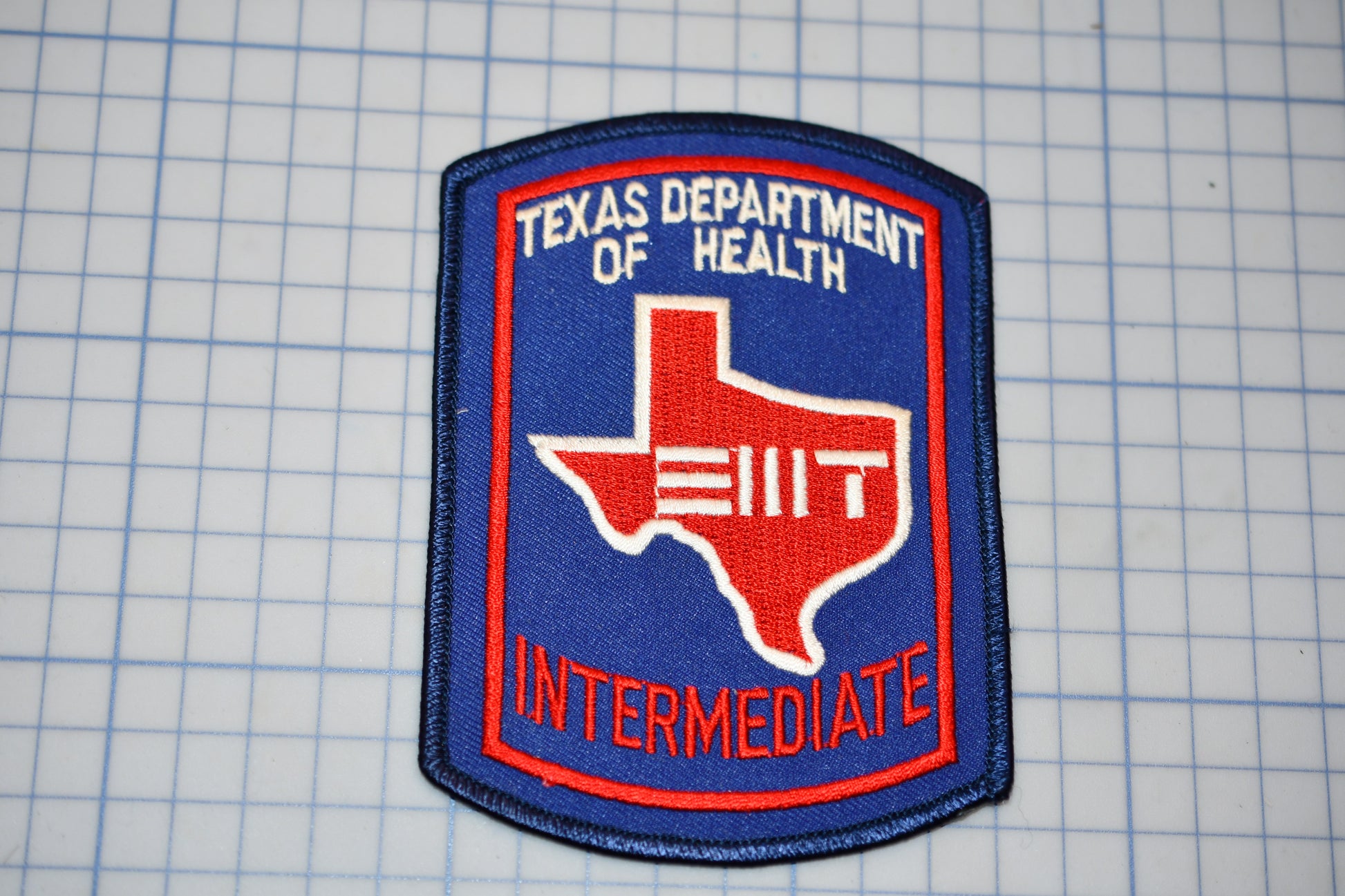 A Texas Department of Health Intermediate patch, featuring the state of Texas and the word "INTERMEDIATE" in red text.