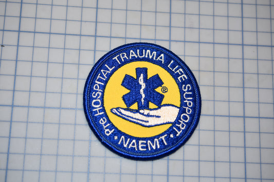 a circular patch with a blue and yellow design, surrounded by text that reads "HOSPITAL trauma life support NAEMT".