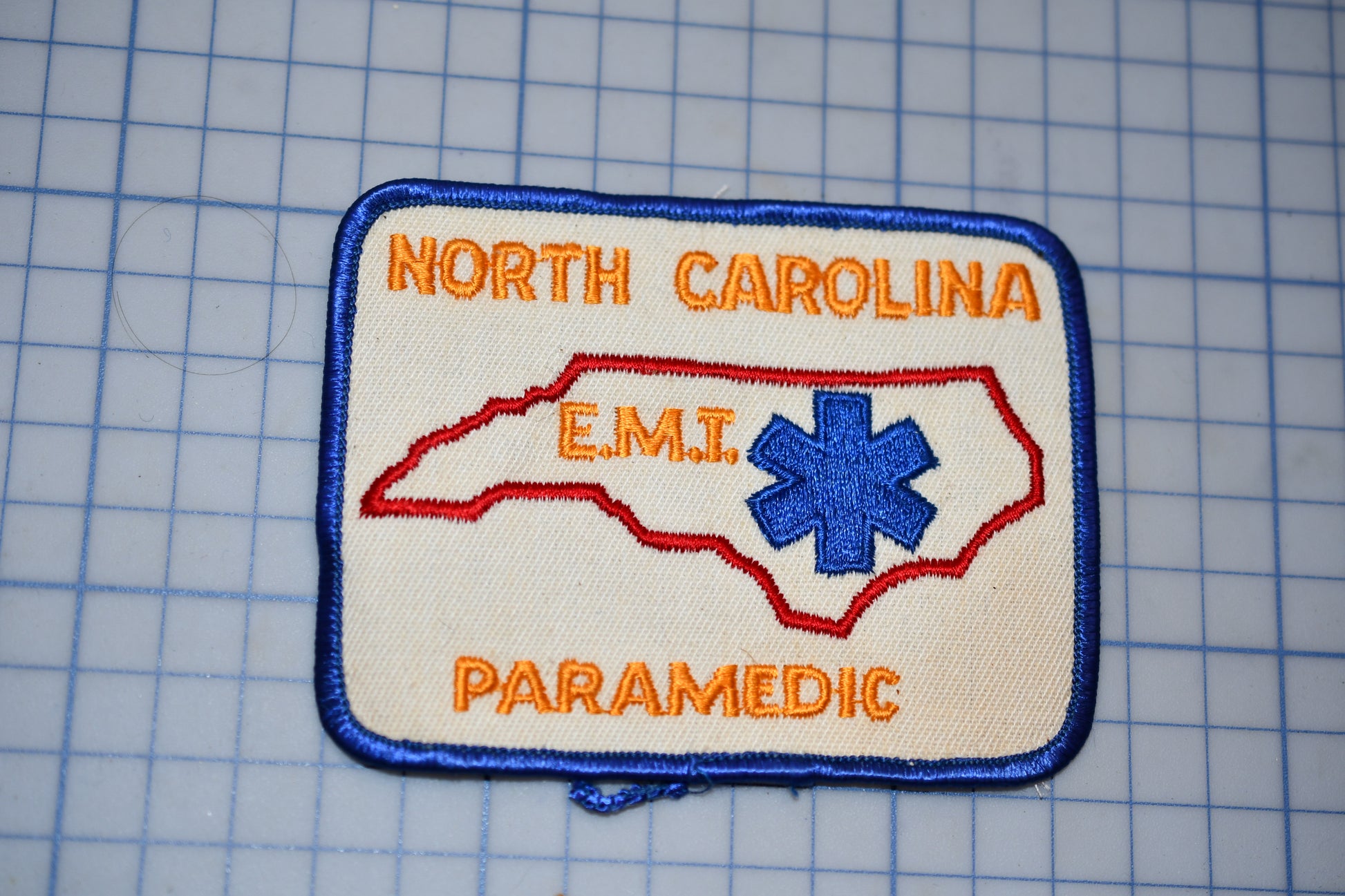 a patch with the text "NORTH CAROLINA EMT PARAMEDIC" and a blue star-shaped symbol, representing the emergency medical services of North Carolina.