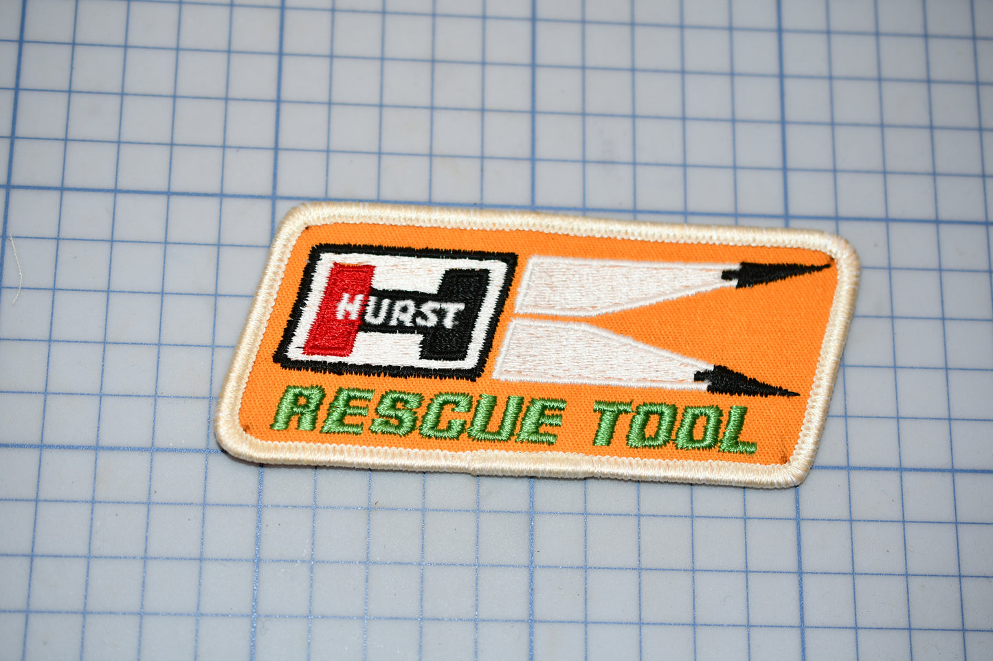 a patch with the word "HURST" and "RESCUE TOOL" printed on it, along with a pair of scissors.
