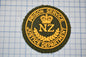 a circular badge with the text "PRISON SERVICE" and "NZ JUSTICE DEPARTMENT" embroidered on it, along with a crown symbol.