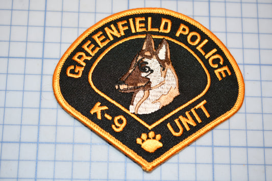 A patch with the text "GREENFIELD POLICE K-9 UNIT" and an embroidered image of a German Shepherd dog.
