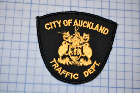 a black and gold patch with the text "CITY OF AUCKLAND" and "TRAFFIC DEPT." on it, indicating that it is a badge or emblem of the City of Auckland's traffic department.