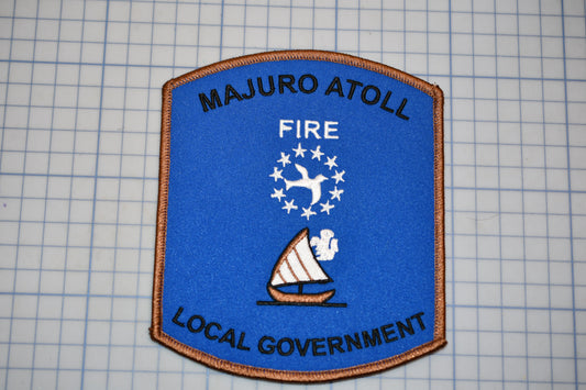a blue and brown patch with text and a sailboat symbol, representing the Majuro Atoll Fire Local Government.