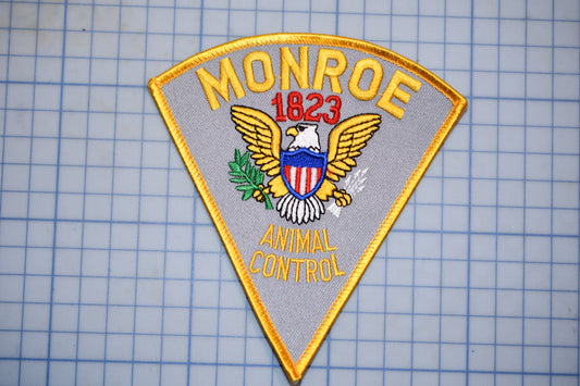 a patch with the text "MONROE 1823" and "ANIMAL CONTROL" on it, along with an eagle and a shield.