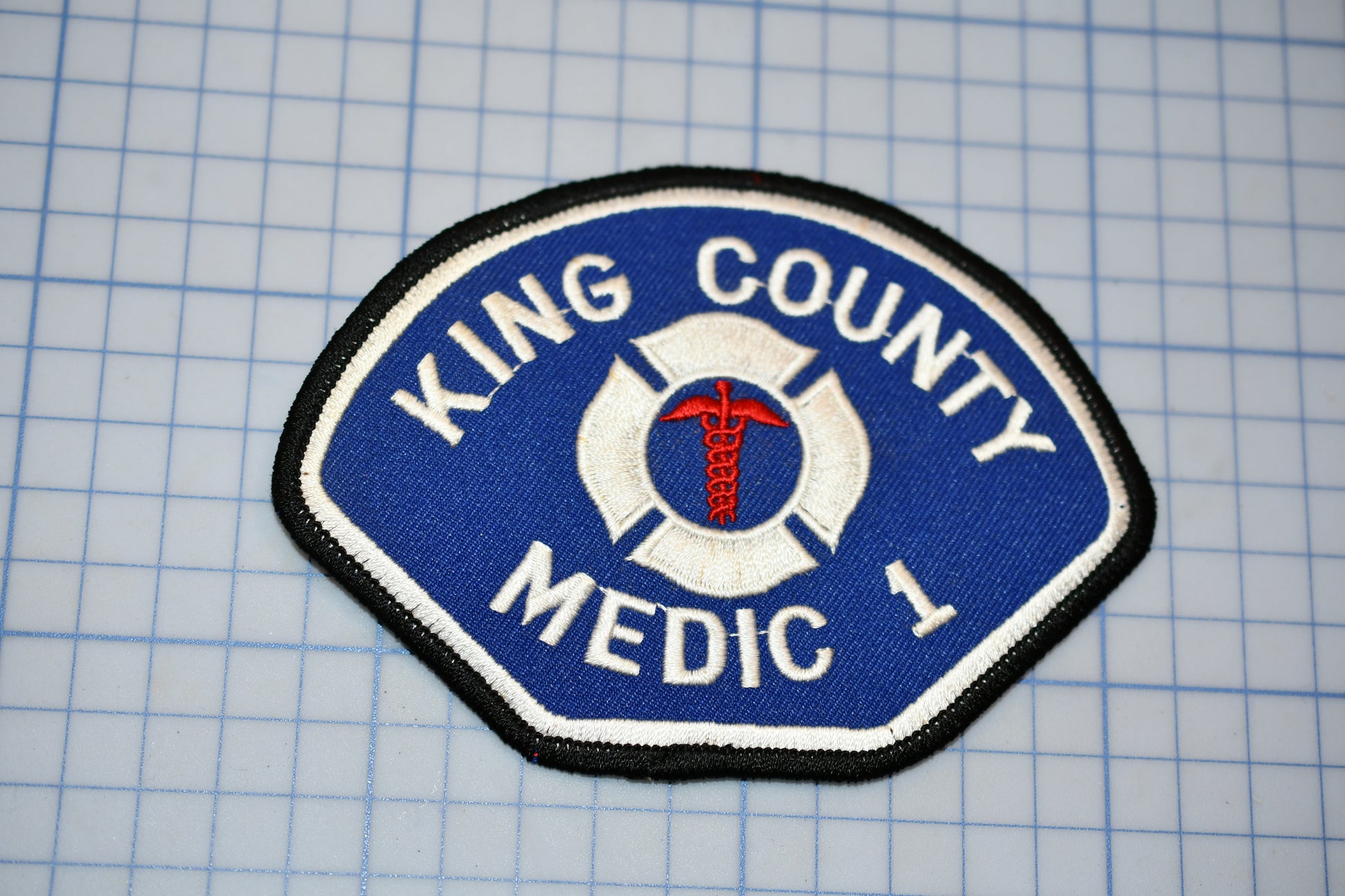 A blue and white patch with the text "KING COUNTY MEDIC 1" and a medical symbol, likely representing a medical emergency response team.