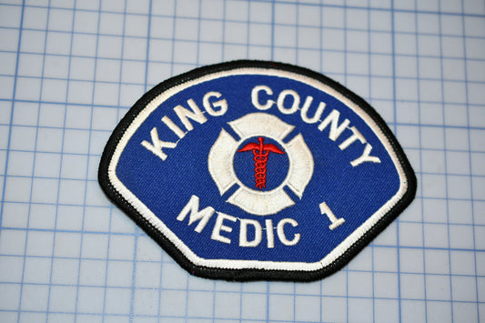 A blue and white patch with the text "KING COUNTY MEDIC 1" and a medical symbol, likely representing a medical emergency response team.