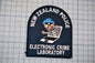 a patch with the text "NEW ZEALAND POLICE ELECTRONIC CRIME LABORATORY" and an illustration of a person wearing a blue hat and holding a laptop.
