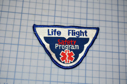 a patch with the text "Life Flight Safety Program" and a medical symbol, indicating it is a safety program related to aviation.
