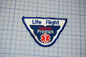 a patch with the text "Life Flight Safety Program" and a medical symbol, indicating it is a safety program related to aviation.
