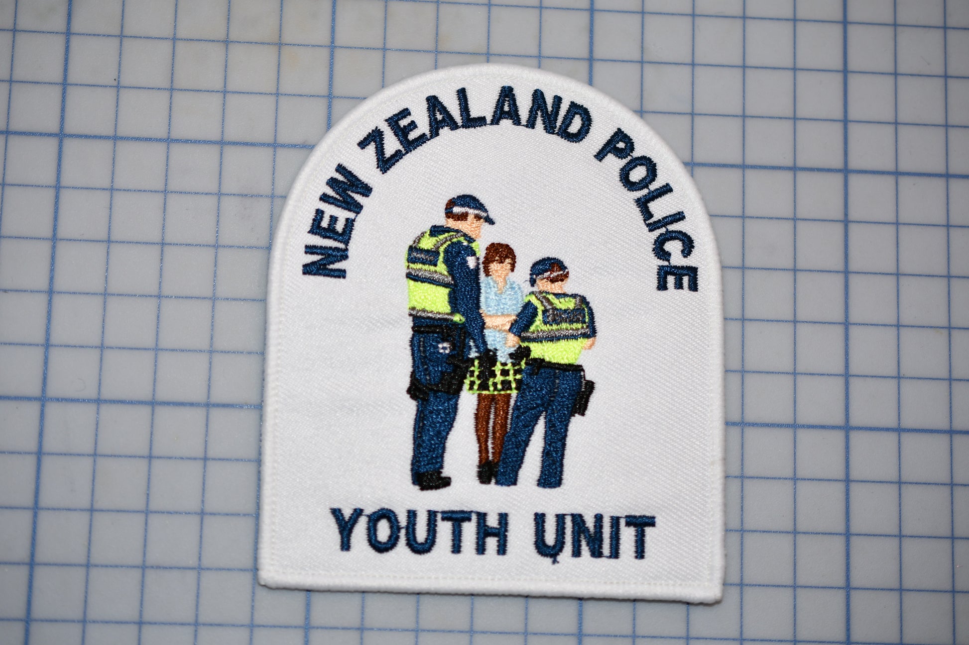 a patch with the text "NEW ZEALAND POLICE Youth Unit" and an illustration of three police officers.