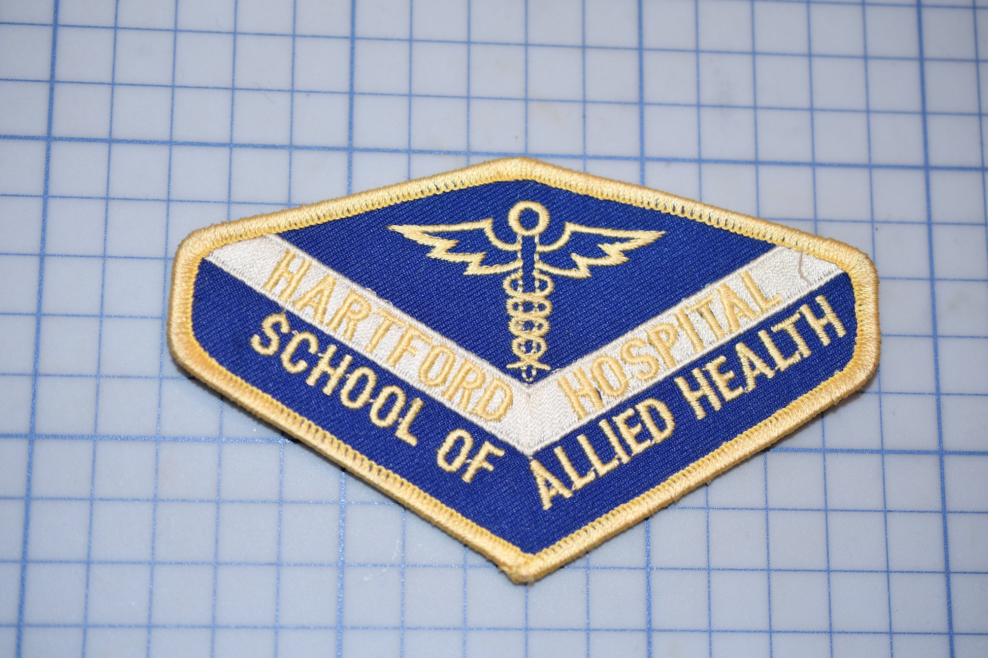 A blue and gold patch with the text "HARTFORD HOSPITAL" and "ALLIED HEALTH" printed on it, along with a medical symbol.