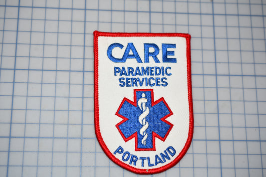 a patch with the text "CARE PARAMEDIC SERVICES PORTLAND" and a medical symbol, likely representing a healthcare organization or institution.