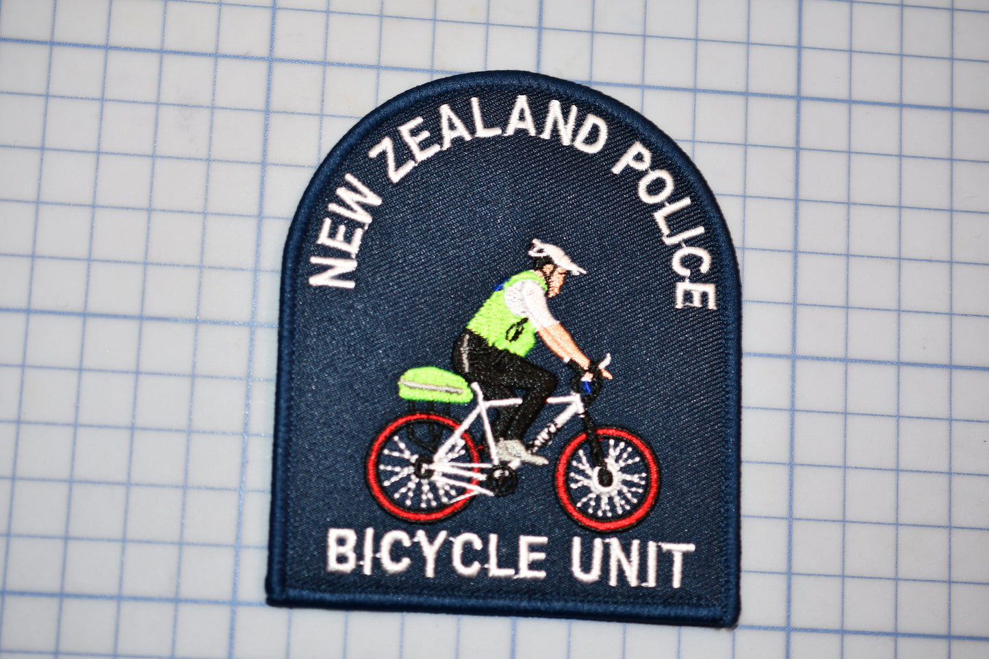 A New Zealand Police Bicycle Unit patch is shown, featuring a police officer riding a bicycle.