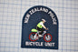 A New Zealand Police Bicycle Unit patch is shown, featuring a police officer riding a bicycle.