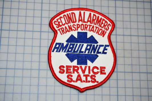 a red and white patch with the text "Second Ambulance Service" and "Ambulance Service S.A.T.S."