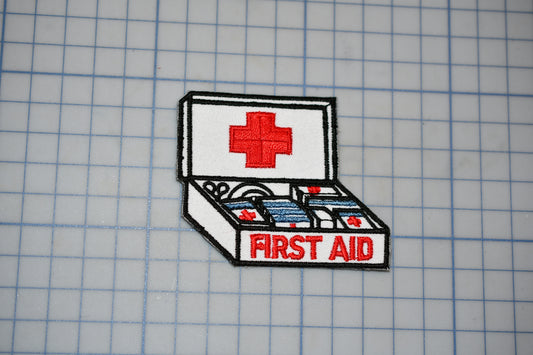 a first aid kit with a red cross symbol on the lid, placed on a grid background.