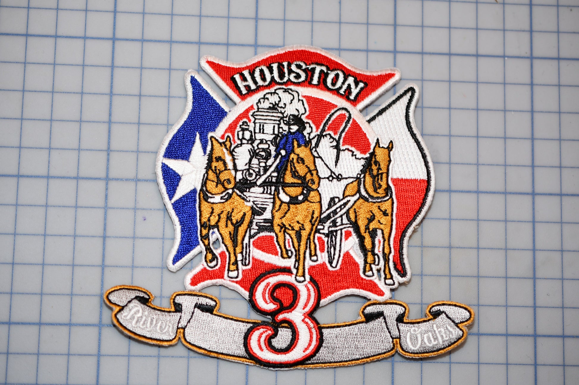 a patch with a fire department emblem, including a fire engine, horses, and a banner with the number 3.