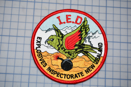 a circular patch with a bird, a bomb, and the text "I.E.D. EXPLOSIVES INSPECTORATE NEW ZEALAND".