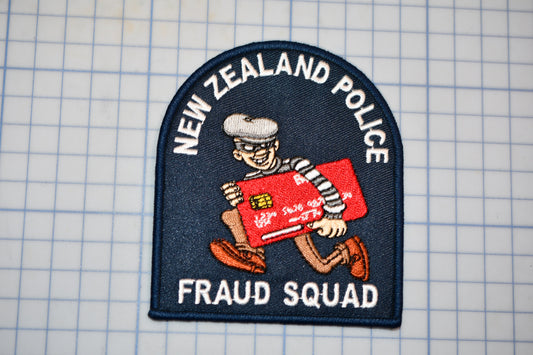 a New Zealand Police Fraud Squad patch, which is a police emblem with a cartoon character holding a stolen credit card.