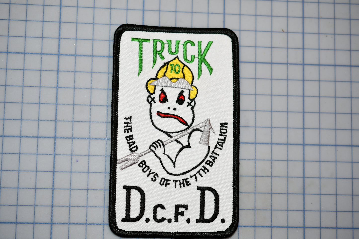 a patch with a cartoon character wearing a fire helmet and holding a fire hose. The patch has text that reads "Truck 10" and "The Bad Boys of the 7th Battalion".