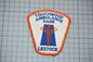 a patch with the text "TOUCHWOOD AMBULANCE CARE LESSTOCK" and an emblem depicting a medical symbol.