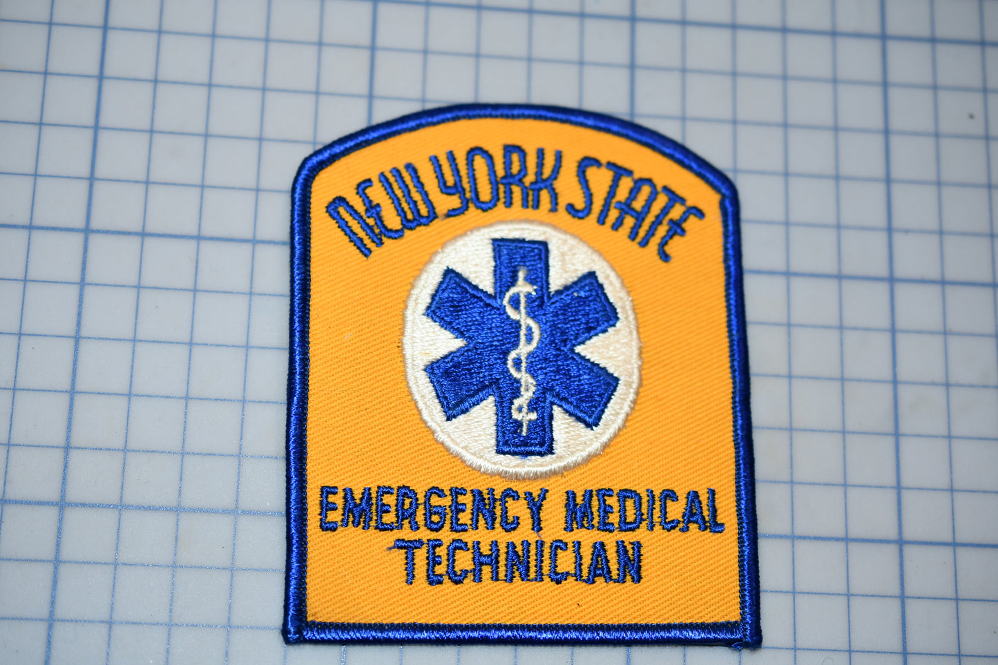 a New York State Emergency Medical Technician (EMT) patch, which is a patch that represents the New York State Emergency Medical Technician program.